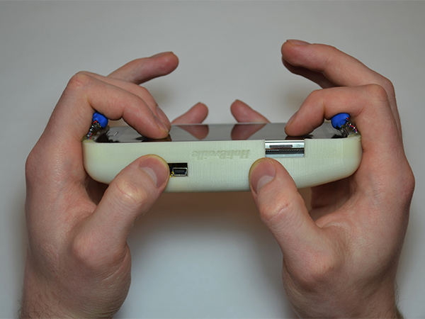 Someone holding a smartphone with both hands. The device is inside a custom case that has 3 small vibrotactile motors on top and bottom. These motors are in contact with the user's fingers.